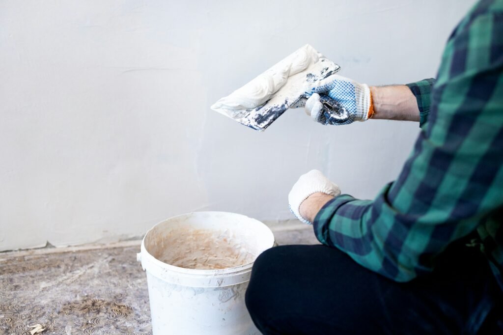 Hands man plasterer construction worker at work with trowel, plastering a wall, closeup.