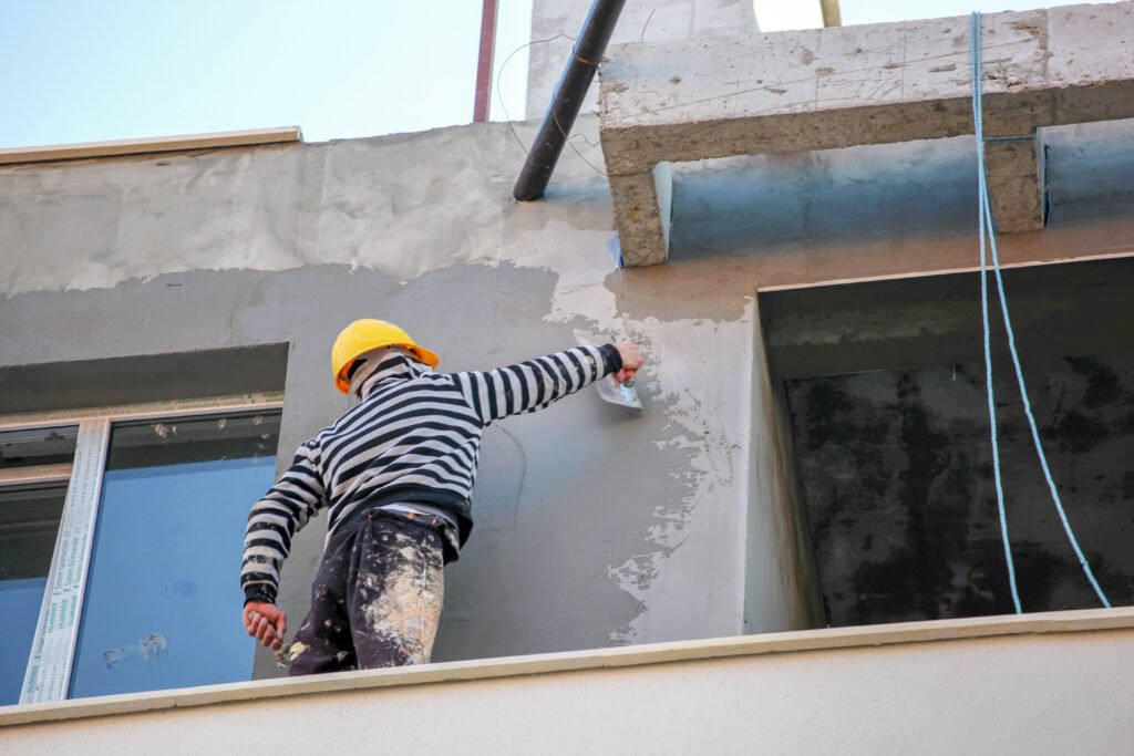 Plasterer concrete worker at wall of house construction