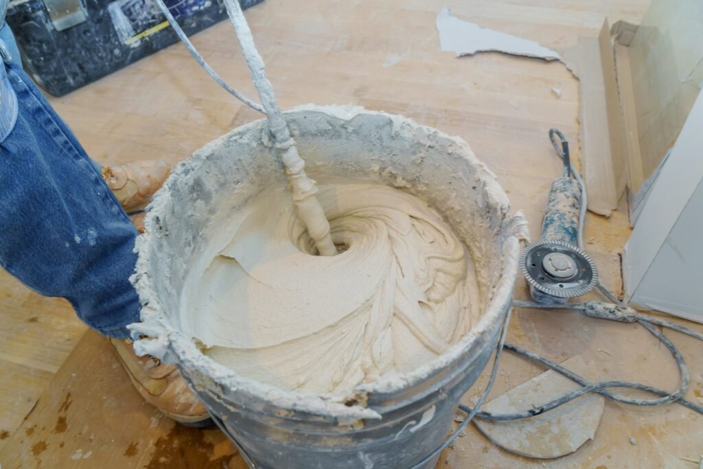 Construction worker mixing tile adhesive or cement with a power drill