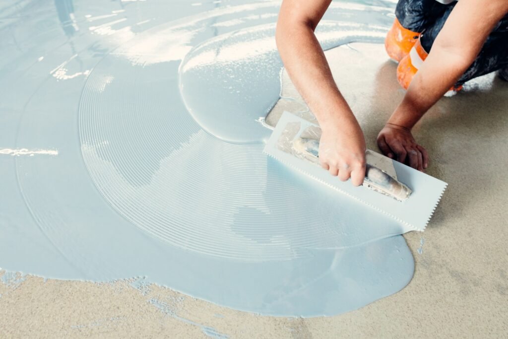 Construction worker spreading self-leveling concrete on the floor using a trowel