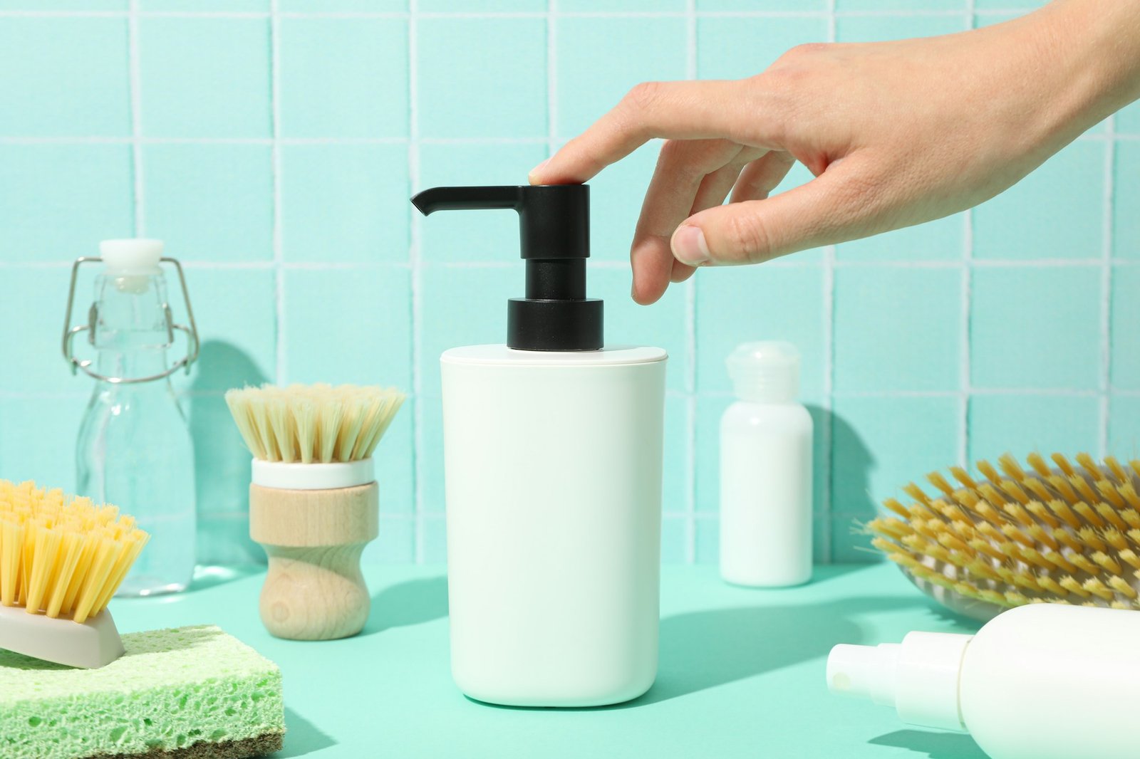 Dispenser for soap, hand, brushes and bottle on blue background