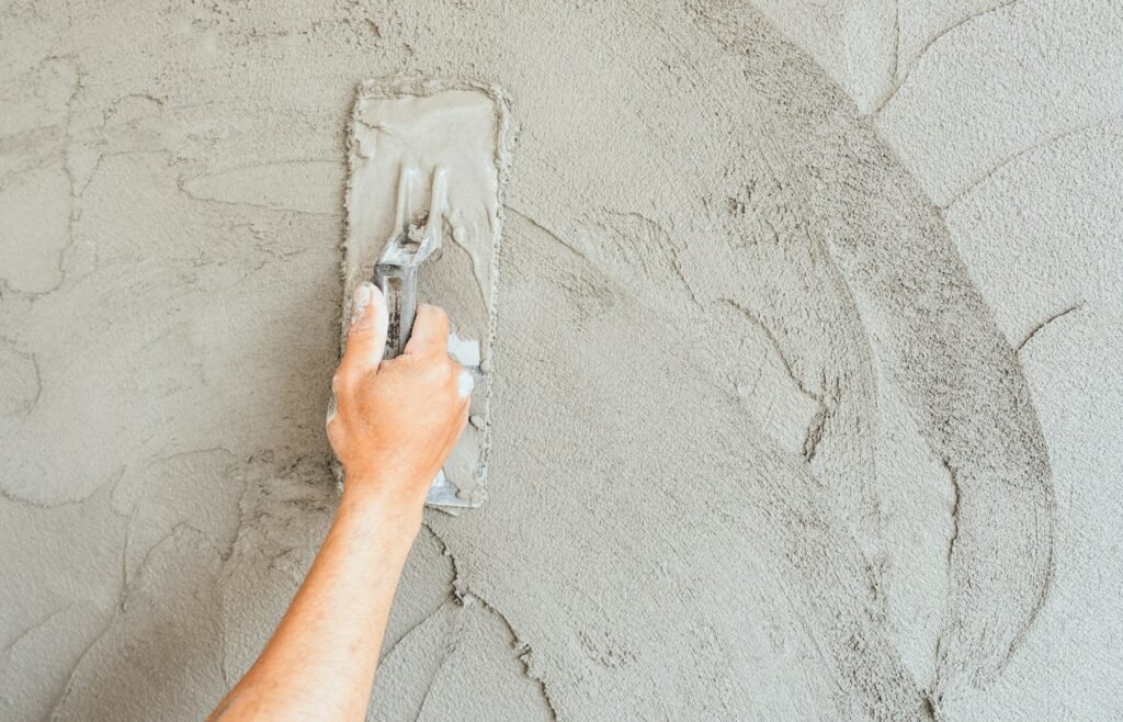 Hand plaster plastering with trowel handle wet grey cement wall background well free space for text