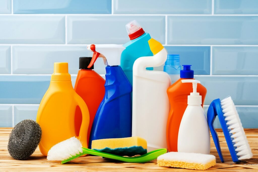 Household detergents and cleaning tools against blue tile background