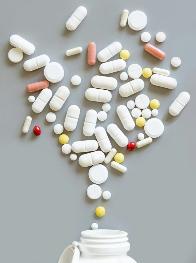 Mix of medical capsules and pills fall out of a bottle on grey top view. Medicinal treatment