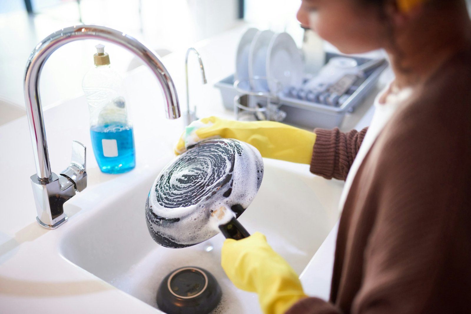 Shot of a young woman washing the dishes at home