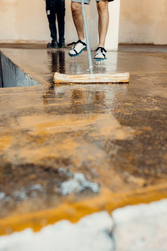 Worker applies floor primer with special tool