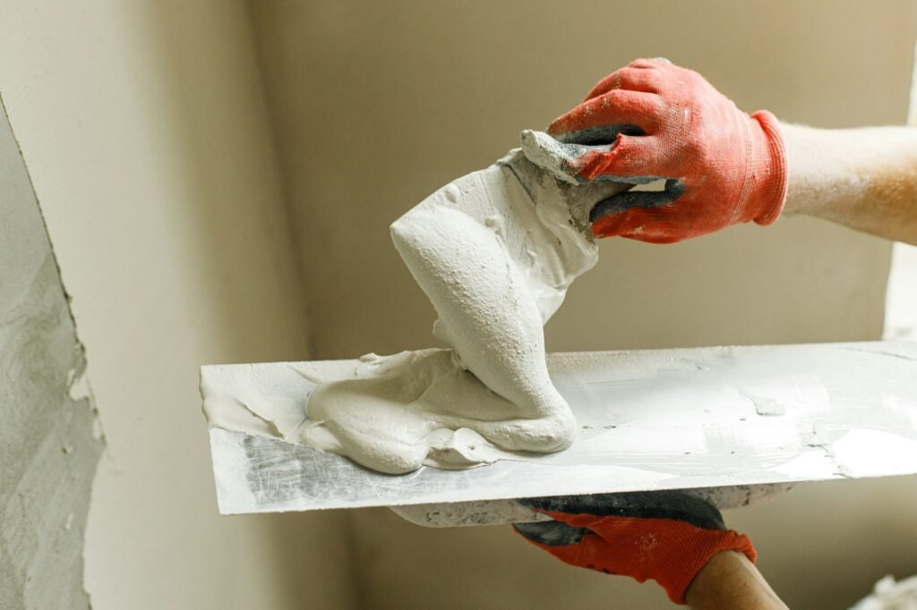 Worker plastering walls with gypsum plaster and spatula