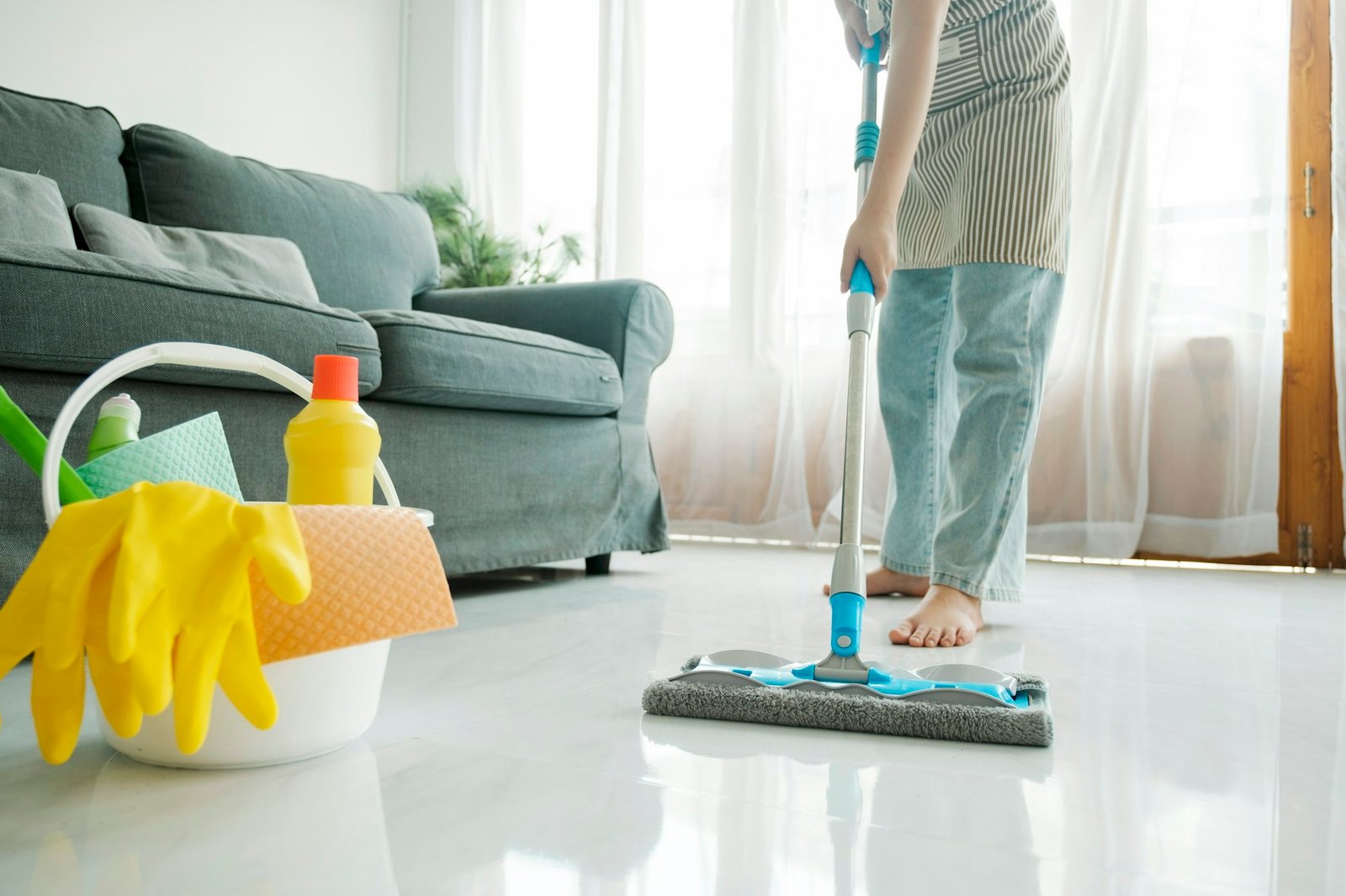 Young woman cleaning floor using mop at home.